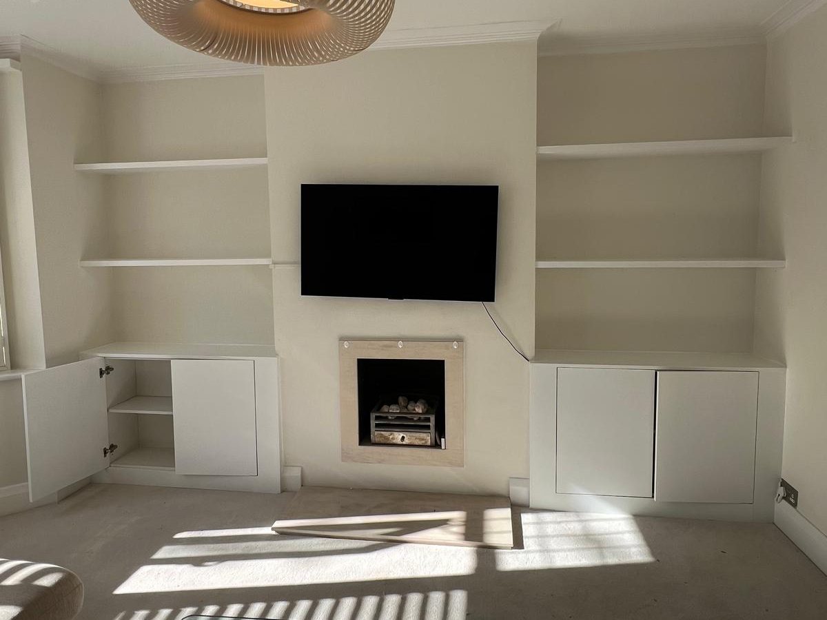 White alcove cupboards with floating shelves either side of a fireplace