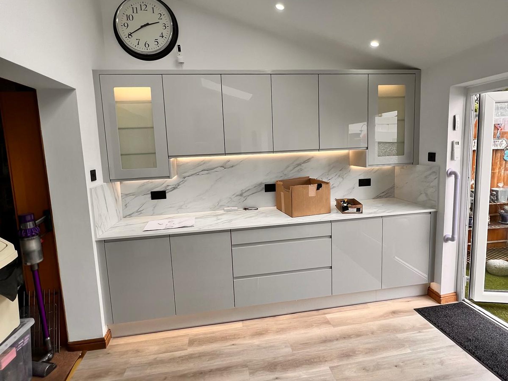 Grey gloss kitchen with a marble effect splashback under a skylight